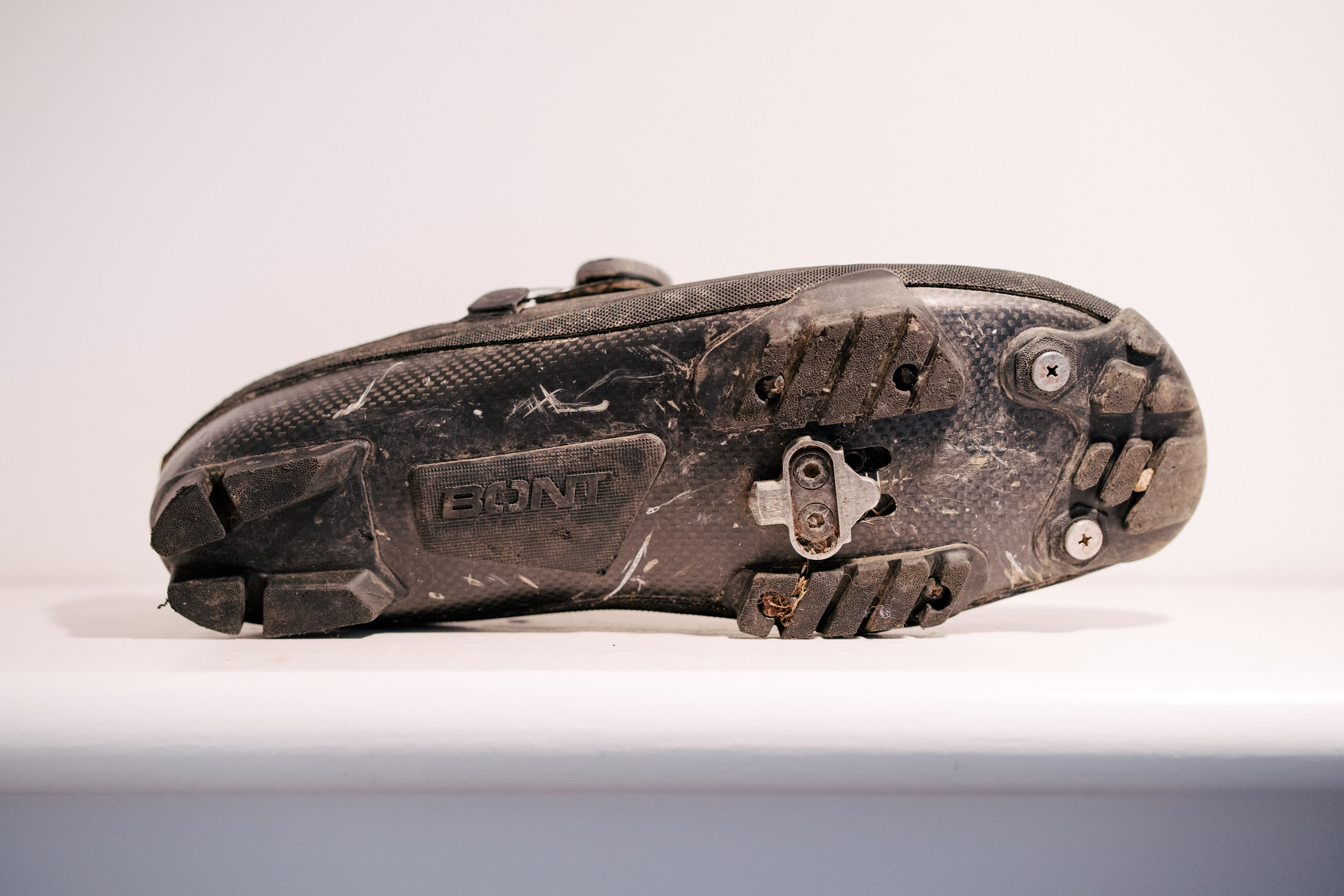 A black, muddy gravel shoe on a white shelf