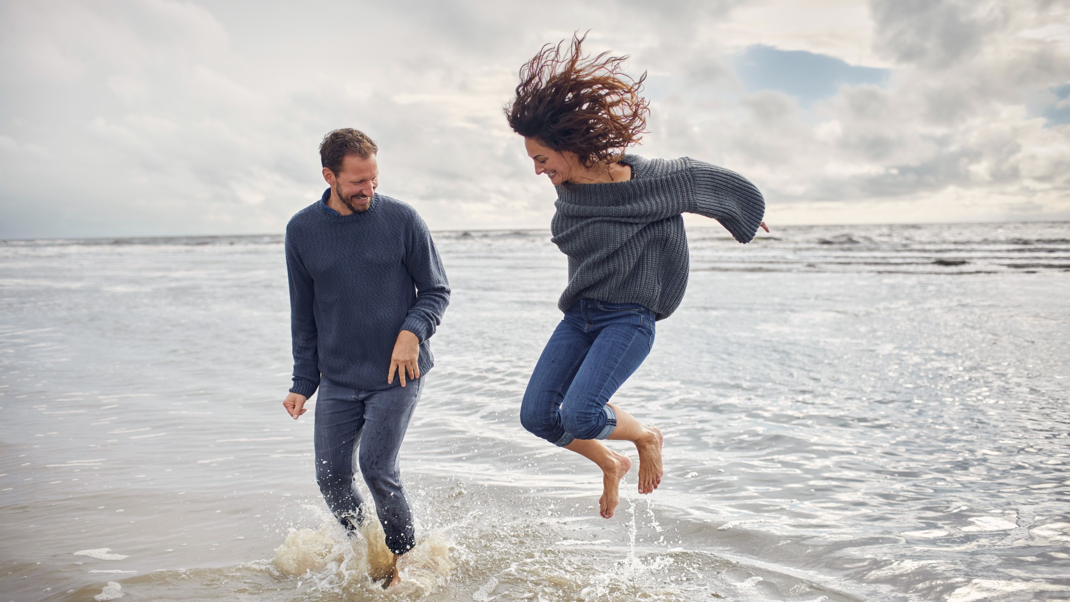 Carefree man and woman jumping in the sea.