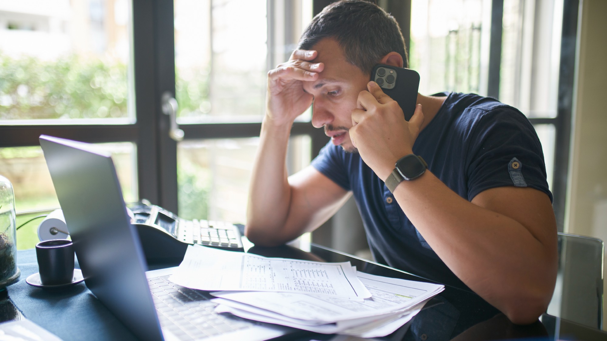 Annoyed man talking on the phone while paying his bills 