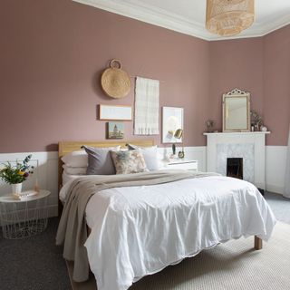 bedroom with dusky pink wall white bed towel rail and fire place