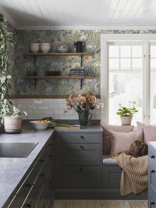 ligh green wallpaper in Scandi style kitchen featuring dark gray cabinets a window seat and a dog