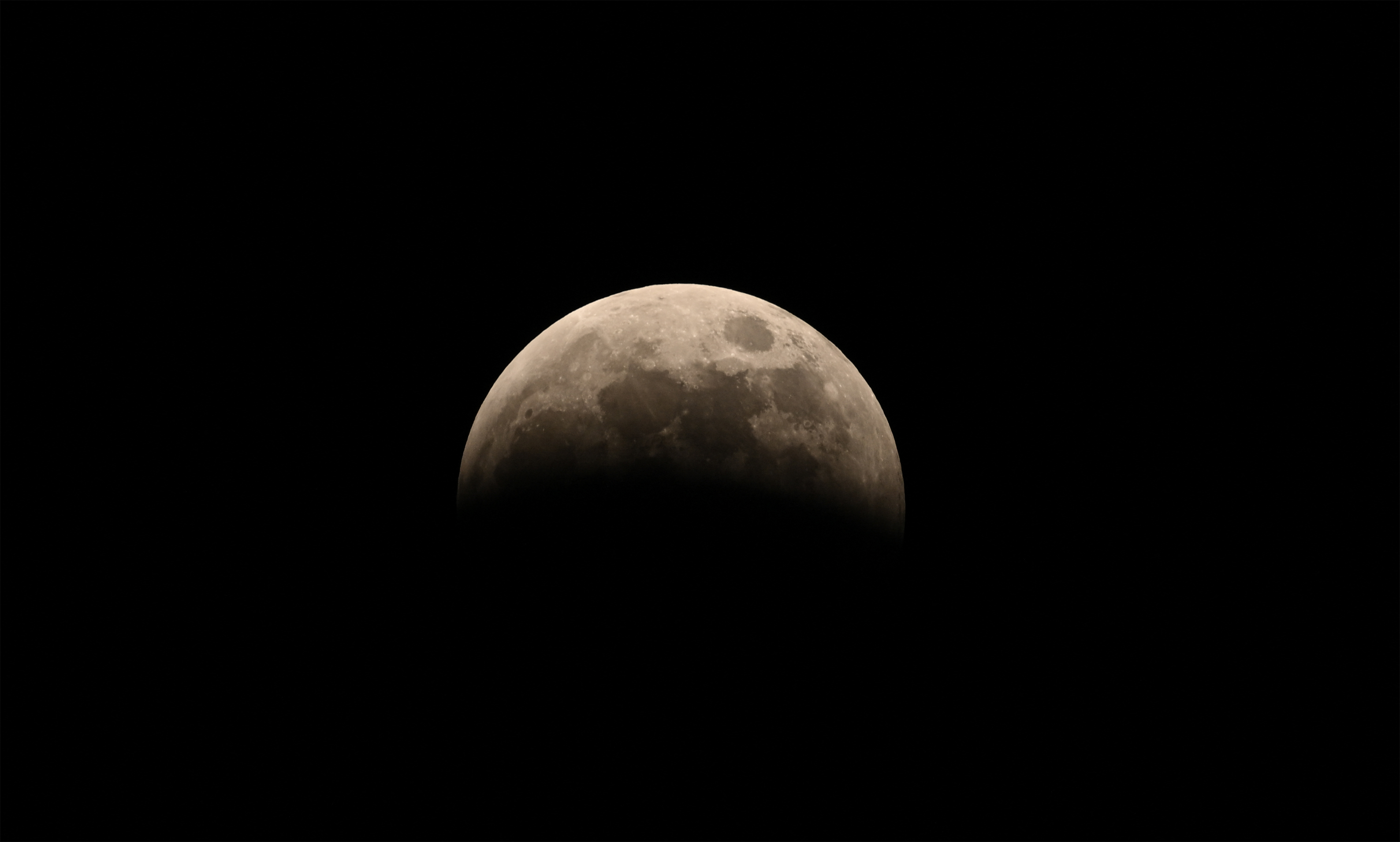 partially eclipsed moon shrouded in Earth's shadow.