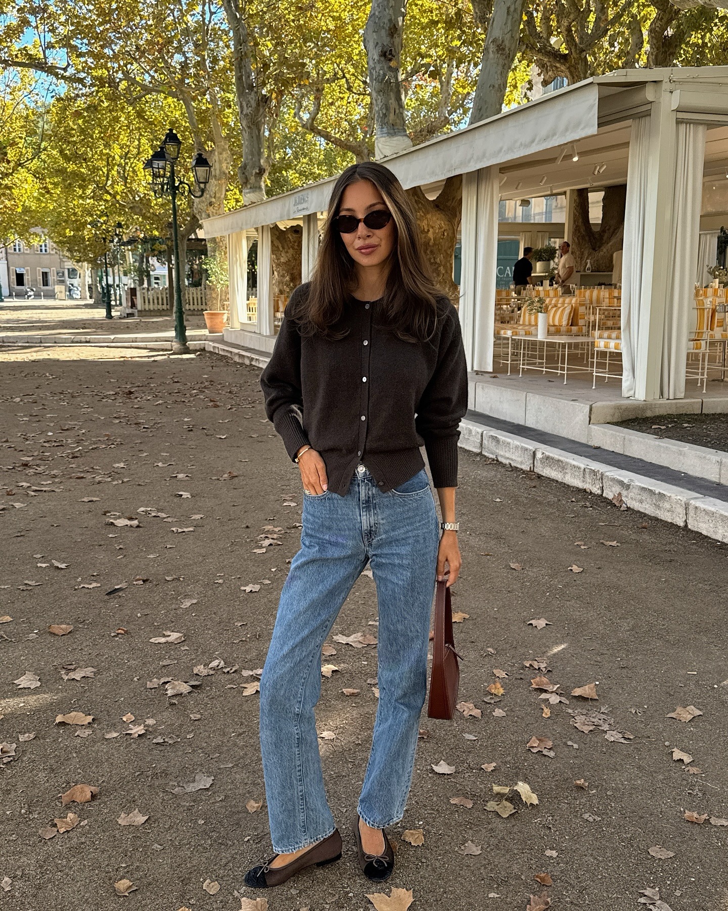 Influencer Felicia Akerstrom wears light-wash jeans with a brown cardigan and ballet flats.