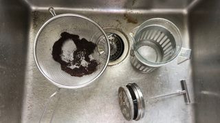 a french press and sieve in the sink being cleaned