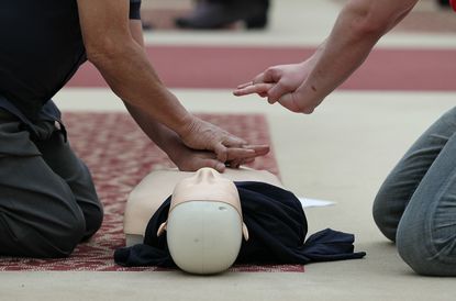 People practice CPR on a dummy.