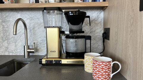 coffee machine on countertops with mugs.