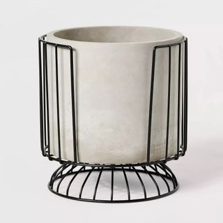 A ceramic white plant pot in a black metal frame stand