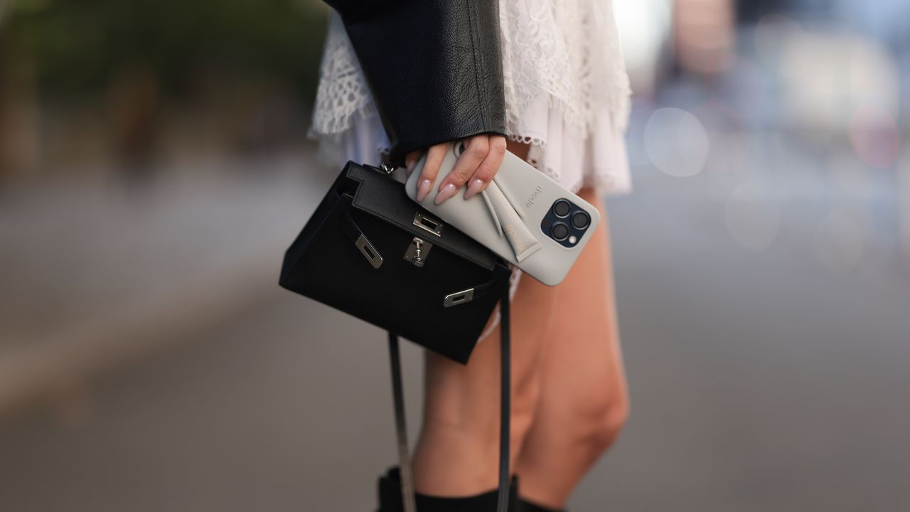 woman holding a rhode phone case, black hermes handbag with muted nails - best nail strengtheners