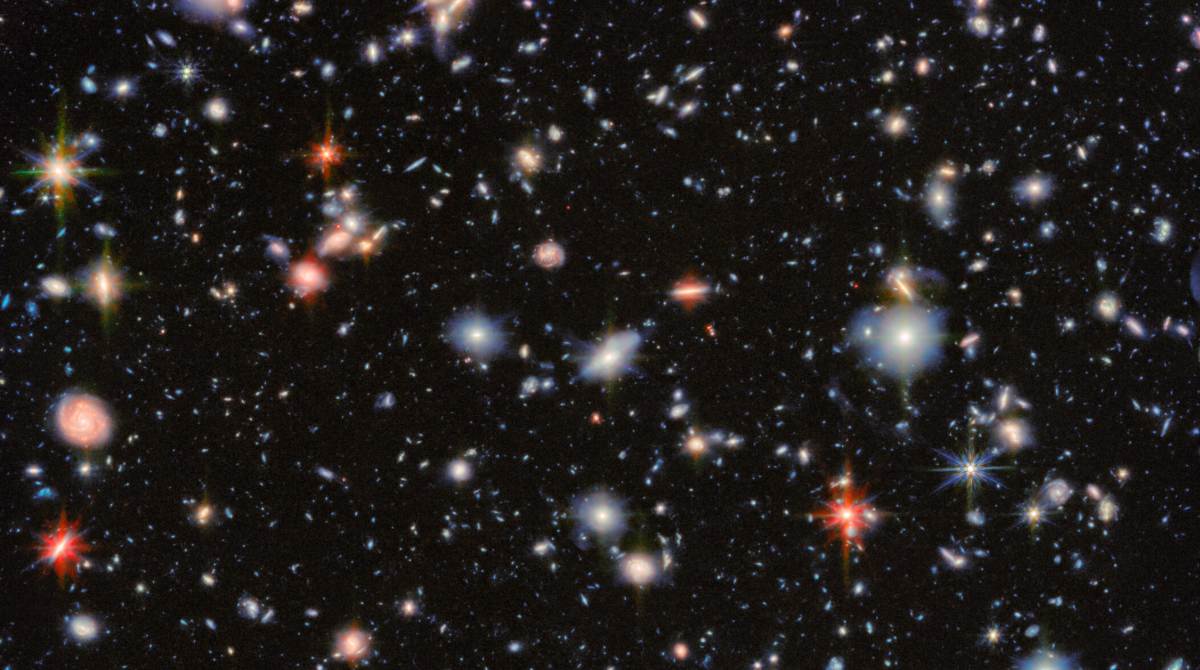 An image of deep space, showing glows of distant stars and swirls of galaxies of many different colors. 
