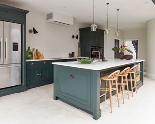 Kitchen scheme in deep tonal greens with focal point island and wooden bar chairs