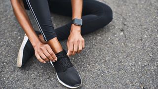 woman lacing up running shoes wearing fitness tracker