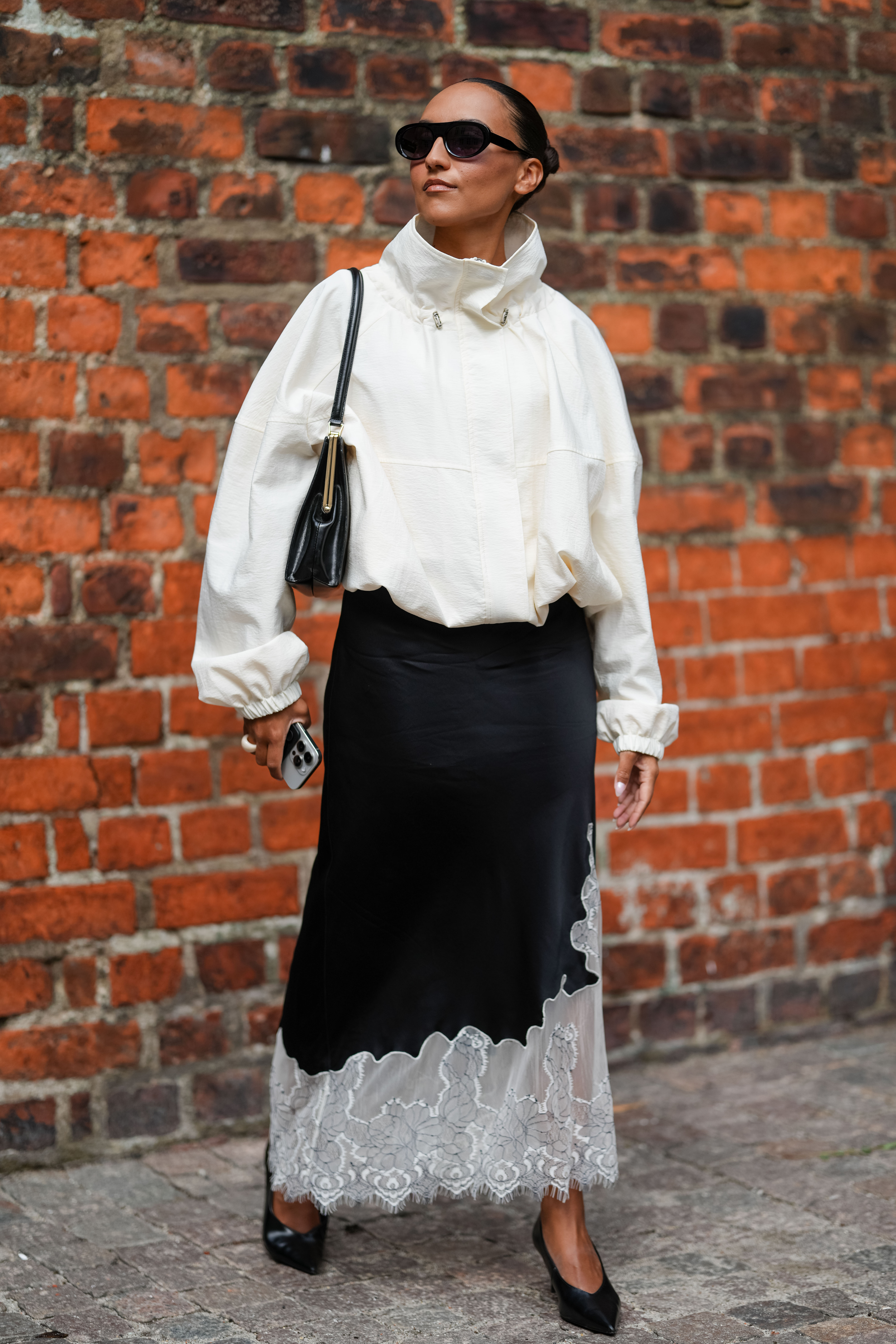 Woman in white funnel neck jacket and lace-trimmed black silk maxi skirt