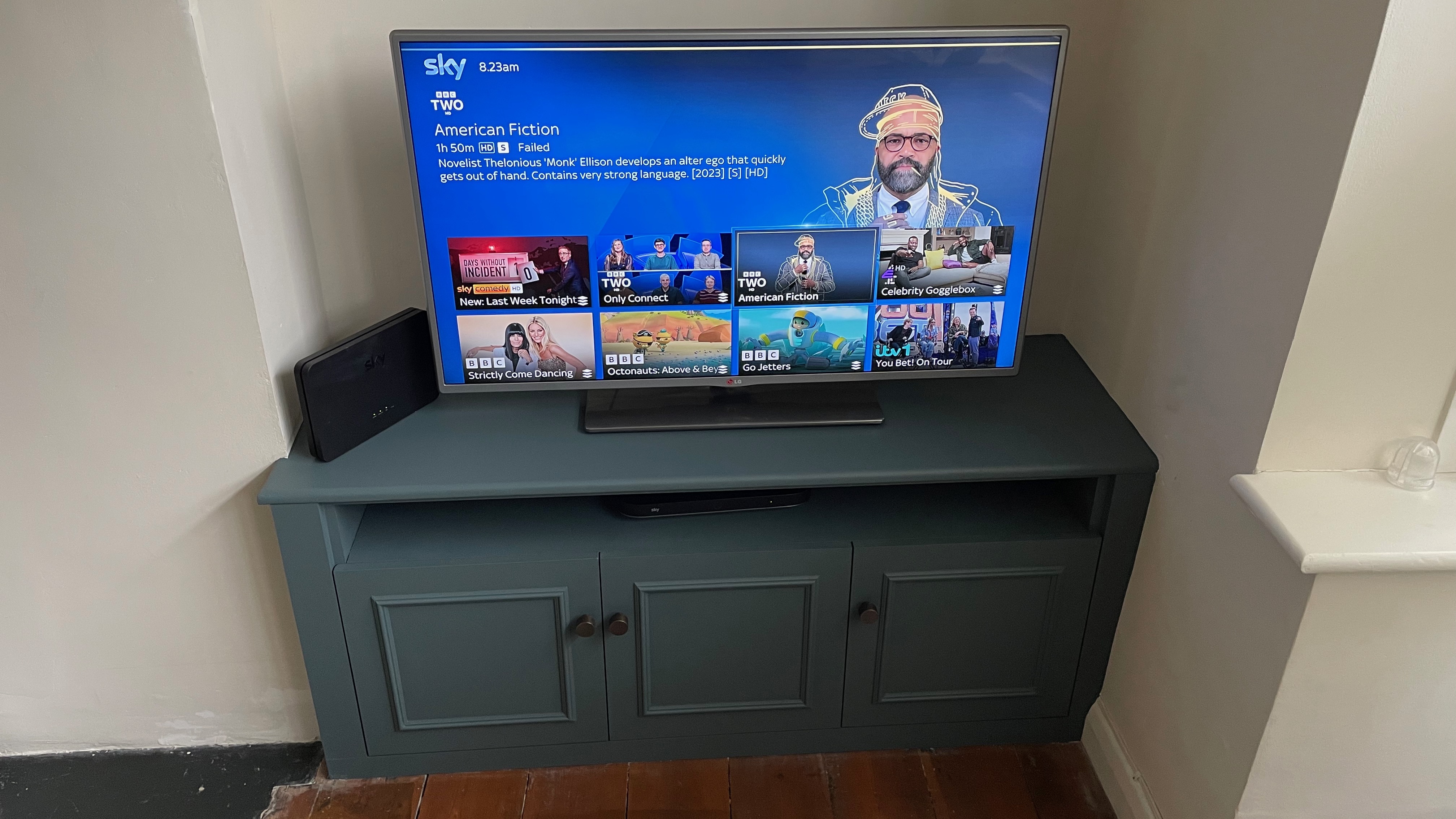 An LG TV on a bespoke TV cabinet, with the title screen of American Fiction on Sky on the screen.