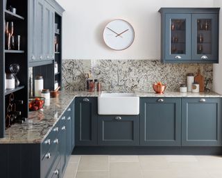 An example of storage in L-shaped kitchen layouts, with blue-gray cabinetry and marble backsplash.