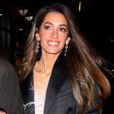 Amal Clooney smiles wearing a black blazer