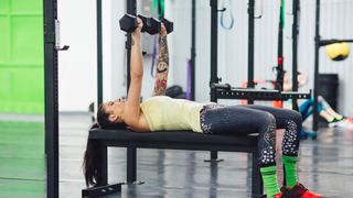 woman performing a dumbbell chest press with a narrow grip