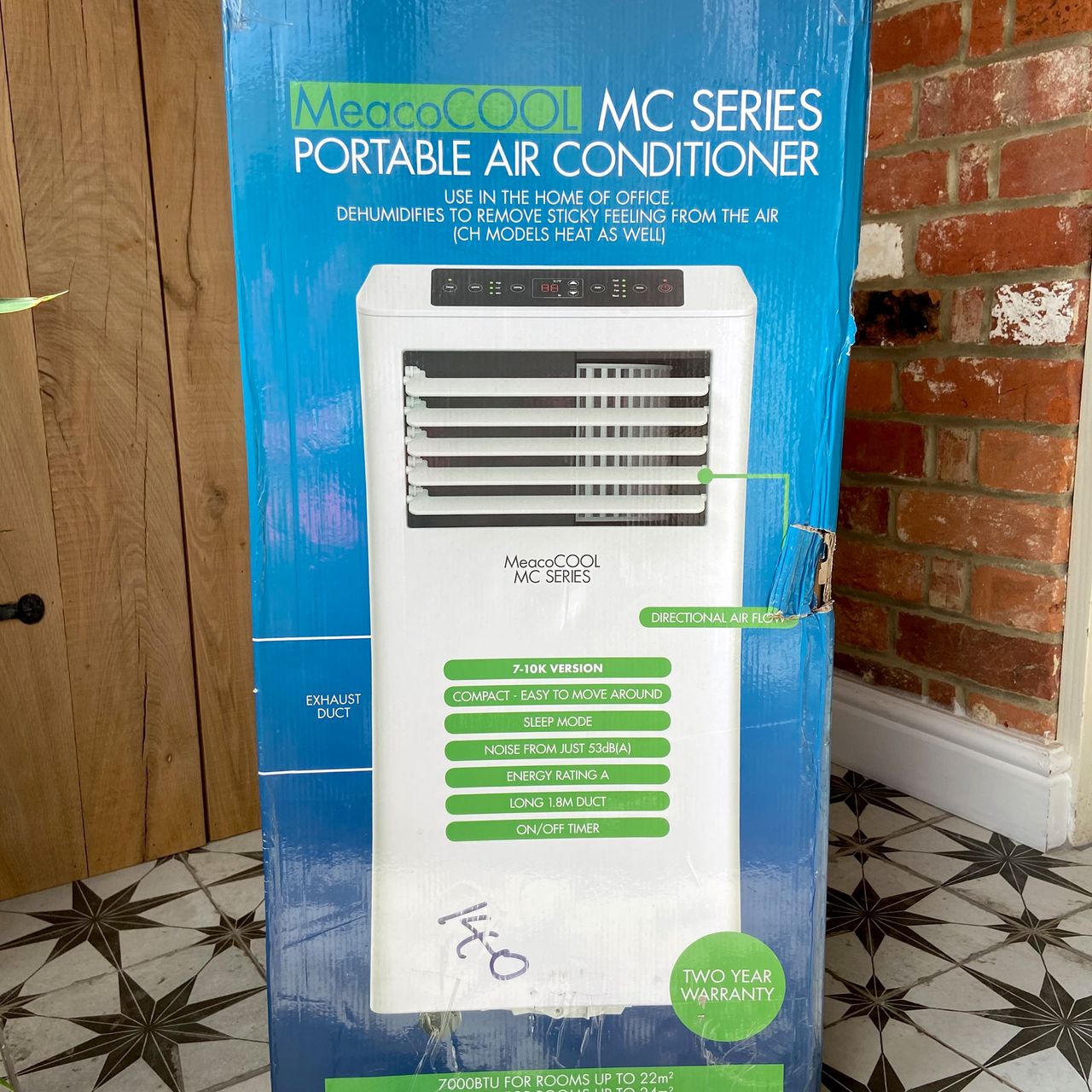 The MeacoCool MC Series 7000BTU Portable Air Conditioner in its blue packaging box in a tiled hallway