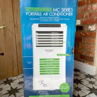 The MeacoCool MC Series 7000BTU Portable Air Conditioner in its blue packaging box in a tiled hallway