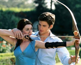 Anne Hathaway shoots a bow and arrow with Chris Pine behind her in 'Princess Diaries 2'