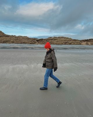 Woman wears country jacket, blue jeans and red hat