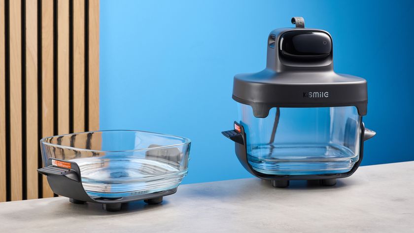 the kismile roasti air fryer with a glass cooking container photographed against a blue and wood background, showing the heating element lid