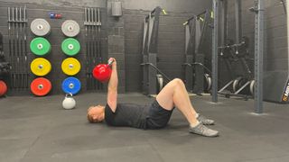 TechRadar fitness writer Harry Bullmore performing a kettlebell single-arm floor press