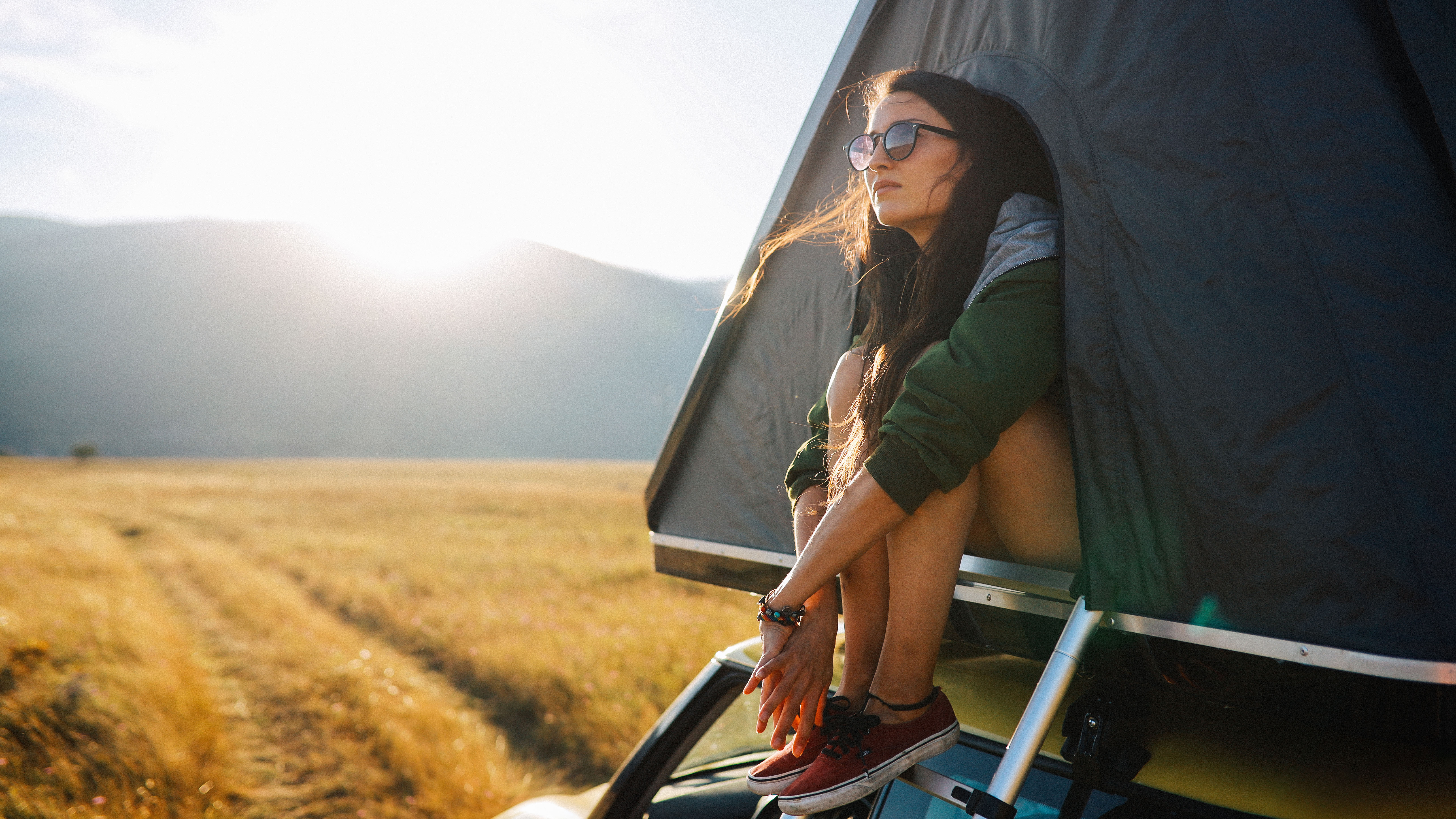 A women sits in the doorway of a rooftop tent