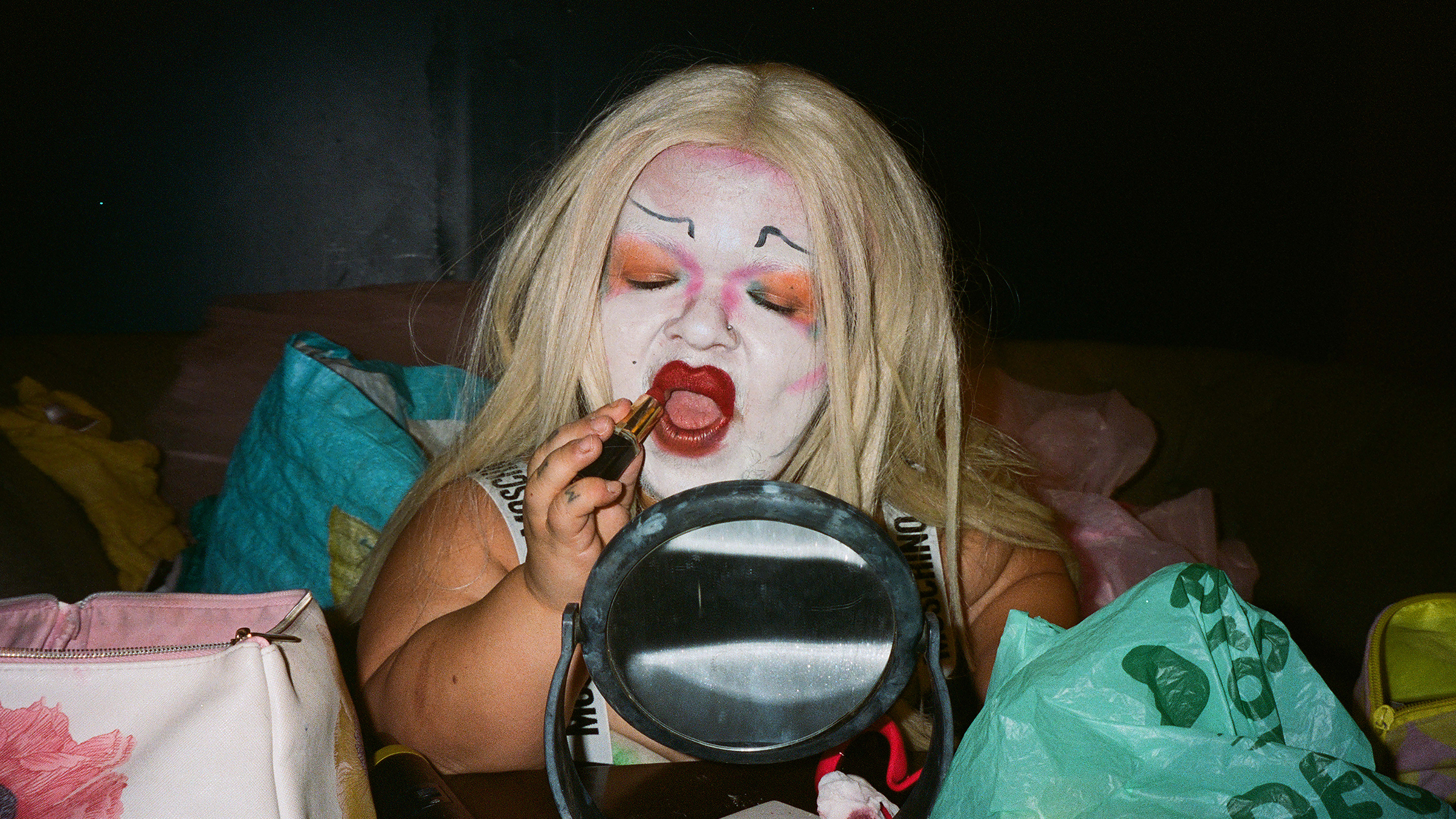Colour photograph of a person applying lipstick in a small mirror