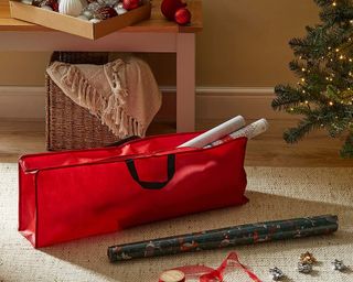 Dunelm Gift Wrap Storage Bag in red beside tree