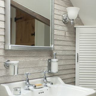 closeup of bathroom basin grey wood panelled wall mirror and classic uplight