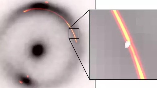 On the left, the Einstein ring is seen in black and white and on the right is an enlarged portion of a section of the ring where the clump is.
