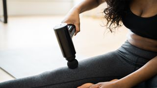 Woman using massage gun on her leg