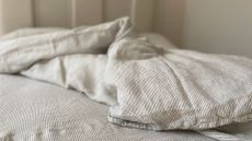 Secret Linen Store Natural Sid Stripe Linen on an unmade duvet