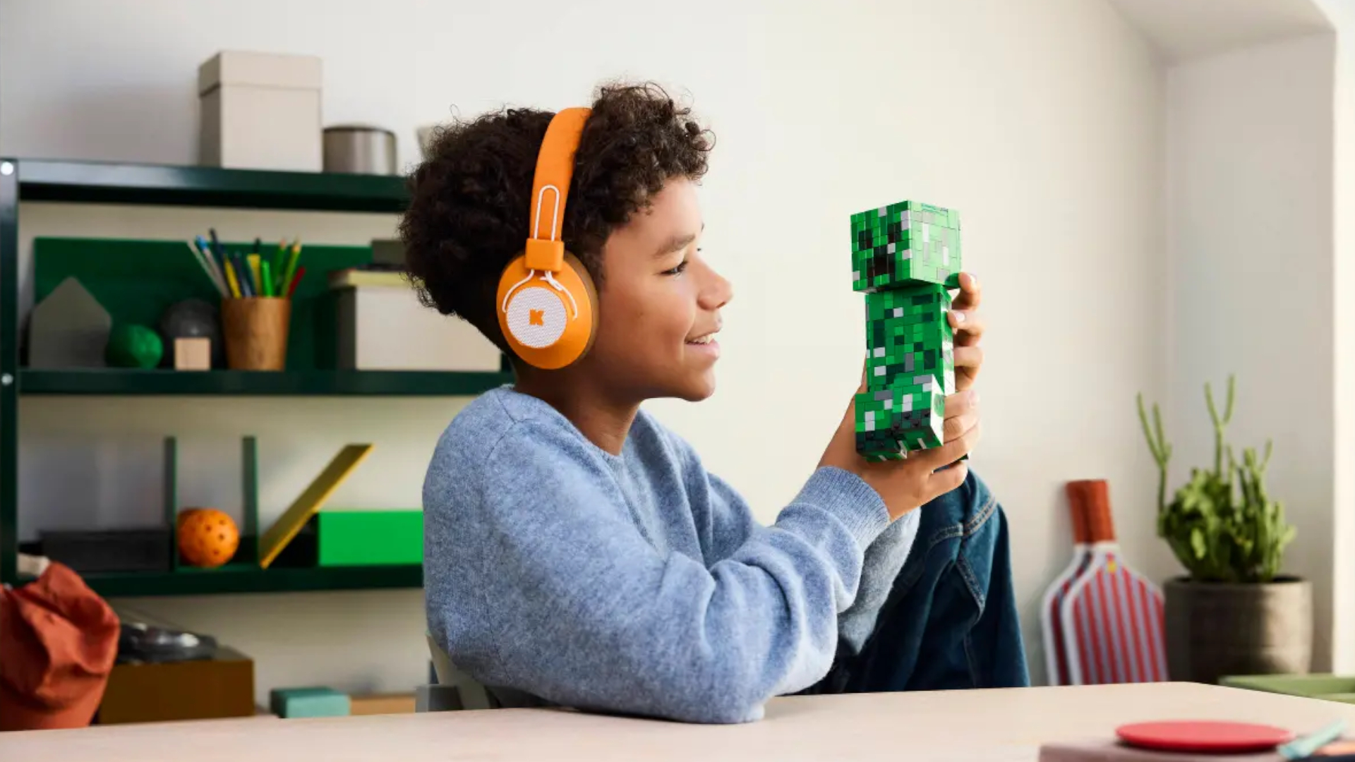 A child smiles at the Lego The Creeper set while wearing headphones, sat at a table