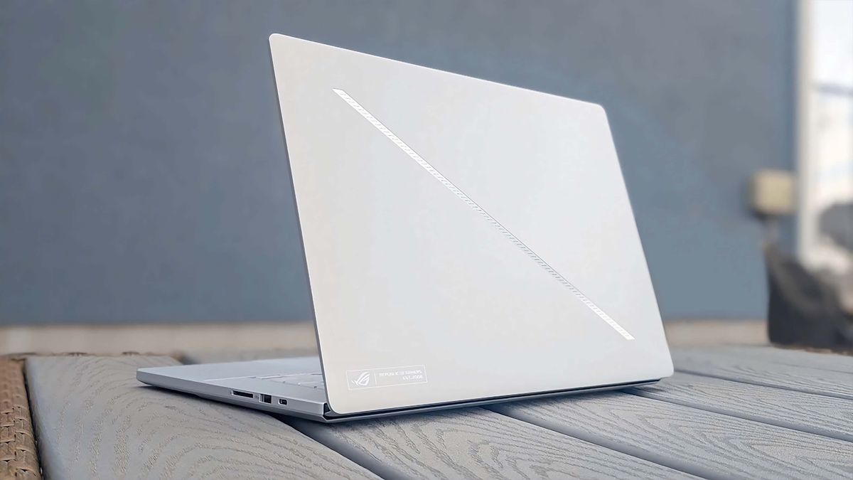 The ASUS ROG Zephyrus G16 (GU605C, 2025) sitting on a grey table and facing away with the slash lighting on the lid.