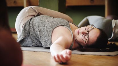 Woman lying on floor performing book opener stretch