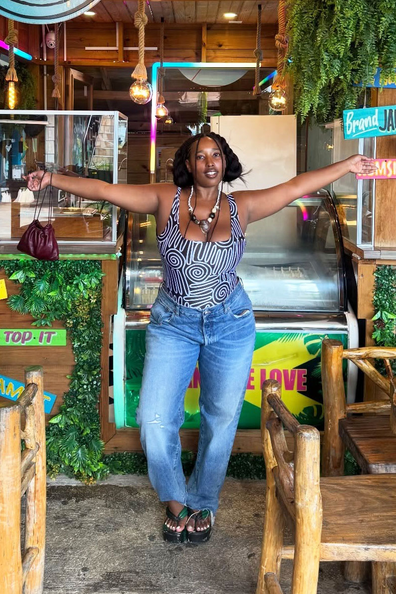 a woman wearing a printed tank top, straight-leg jeans, and flip flops