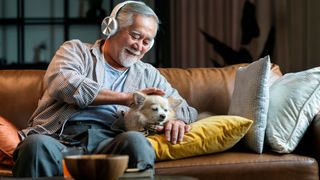Man listening to music with dog on the sofa