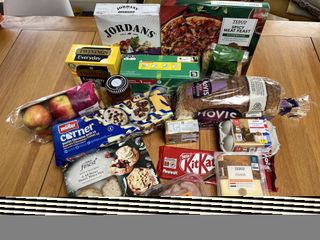 Tesco supermarket haul laid out on a table including KitKats, mince pies and pizza