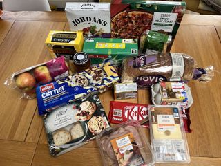 Tesco supermarket haul laid out on a table including KitKats, mince pies and pizza