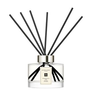 A glass reed diffuser with black reeds and white label