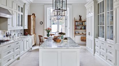 : All white kitchen with kitchen island along the centre and metal frame rectangular lantern ceiling lights