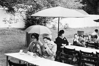 'Women under umbrellas at picnic table