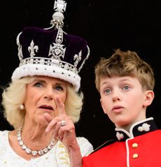 Queen Camilla wearing her coronation crown pointing at something to her grandson Freddy Parker Bowles