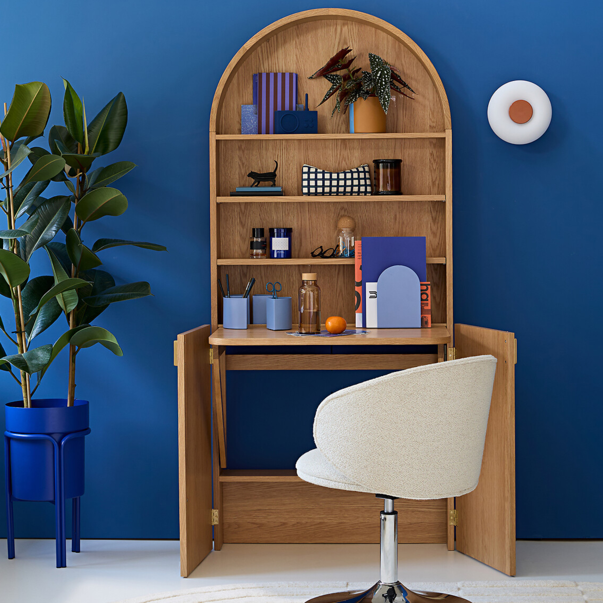 Blue home office with wooden desk that opens out and boucle office chair