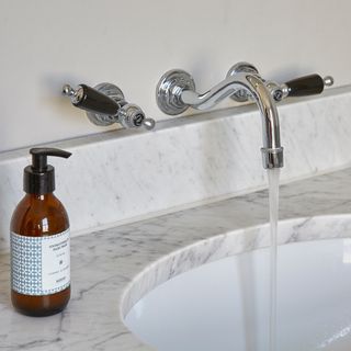 room with curved tap white sink and glass bottle