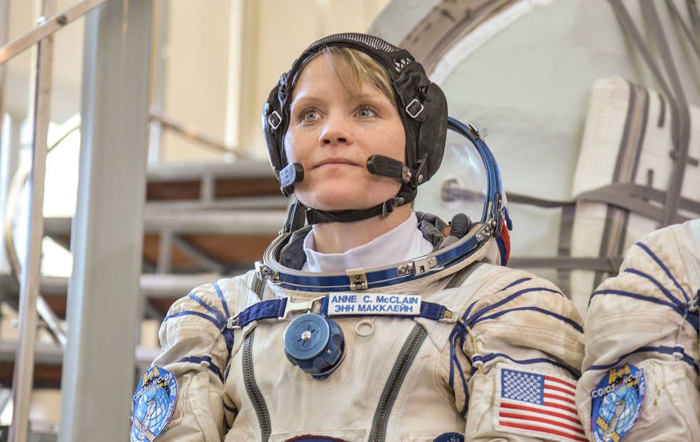 NASA astronaut Anne McClain poses in a spacesuit on Earth.