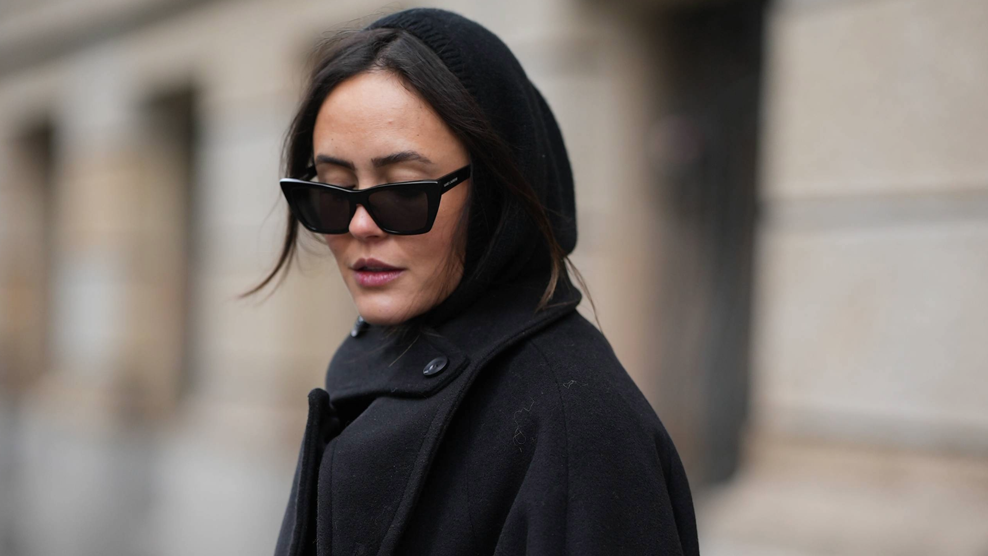 BERLIN, GERMANY - NOVEMBER 25: Laura Noltemeyer is seen wearing a long black oversized wool coat with wide, draped lapels, dropped shoulders and high collar button fastening from The Frankie Shop; a soft black rib-knit balaclava with an integrated neck panel from H&amp;M; black angular acetate sunglasses with a thick frame from Yves Saint Laurent; her dark brown hair is worn loose with a middle part, partially tucked under the balaclava on November 25, 2025 in Berlin, Germany. (Photo by Moritz Scholz/Getty Images)