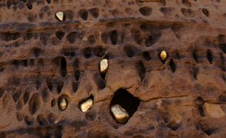 Golden rocks inserted into holes in desert rock face