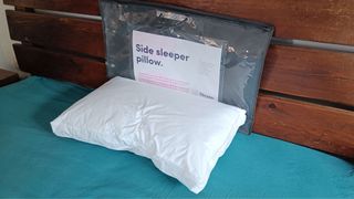 Caramel Quin testing Dreams Side Sleeper Pillow on bed with packaging